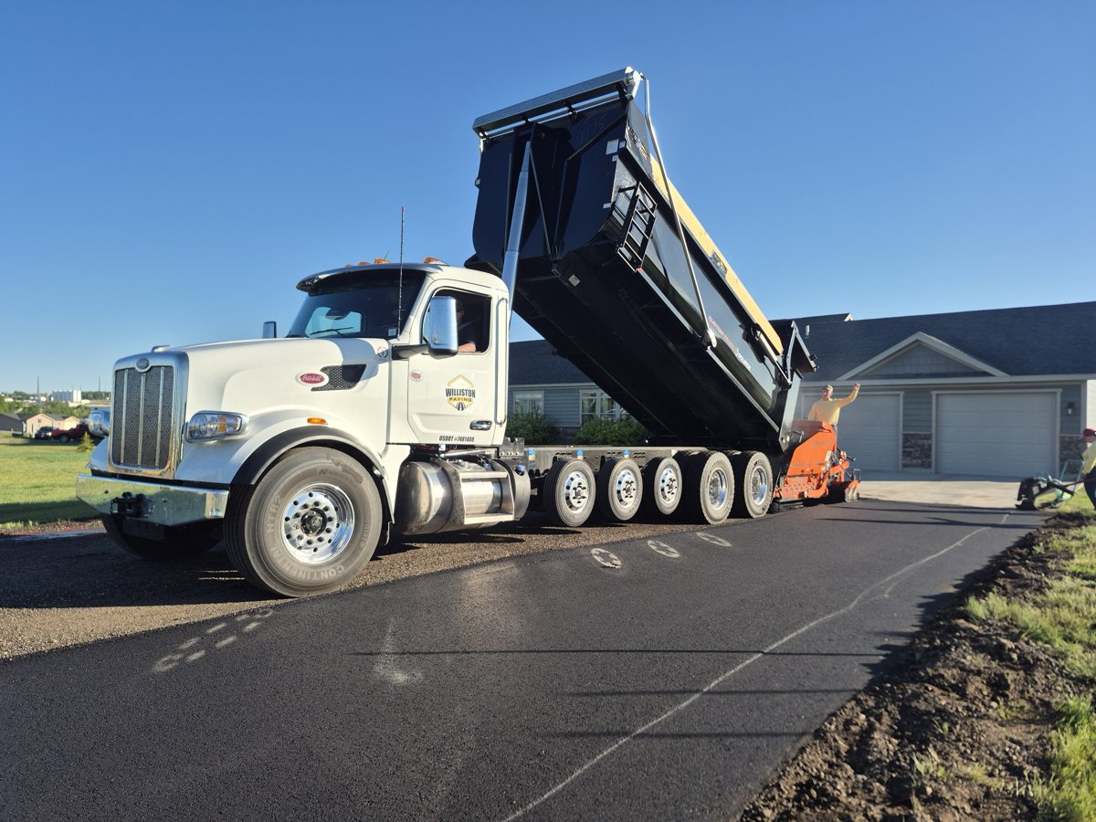 Dump truck feeding an asphalt paver on a Williston, ND job site