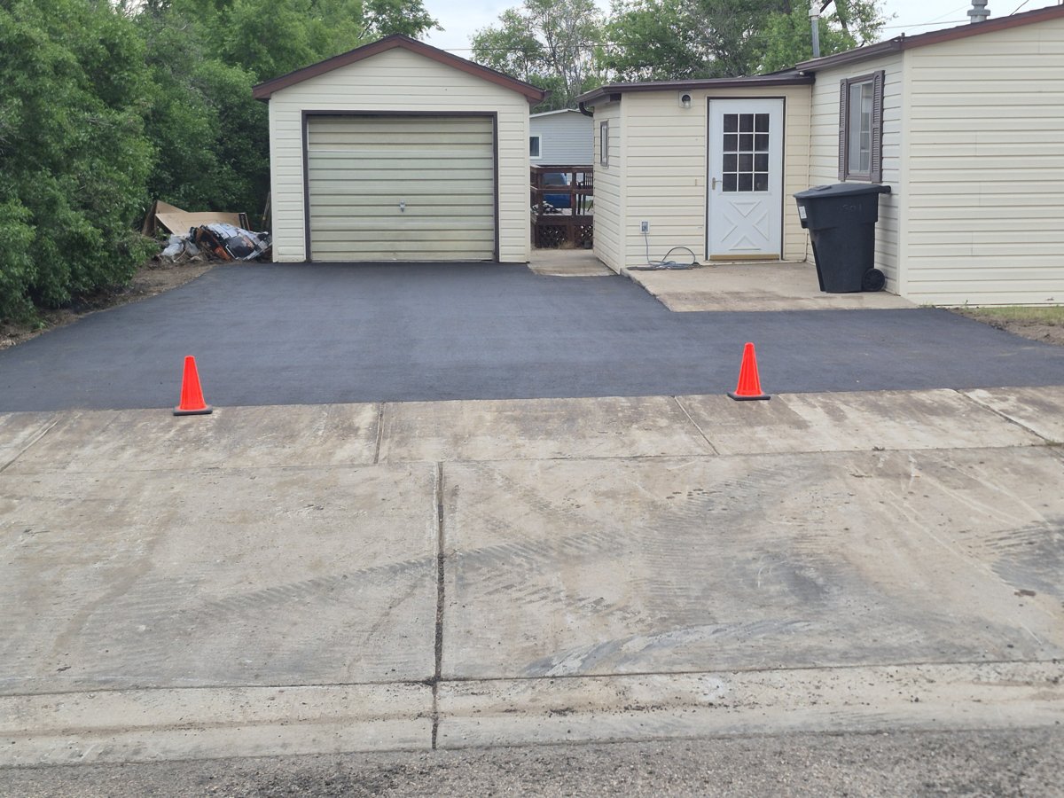 New asphalt driveway leading to an attached garage near Williston, ND