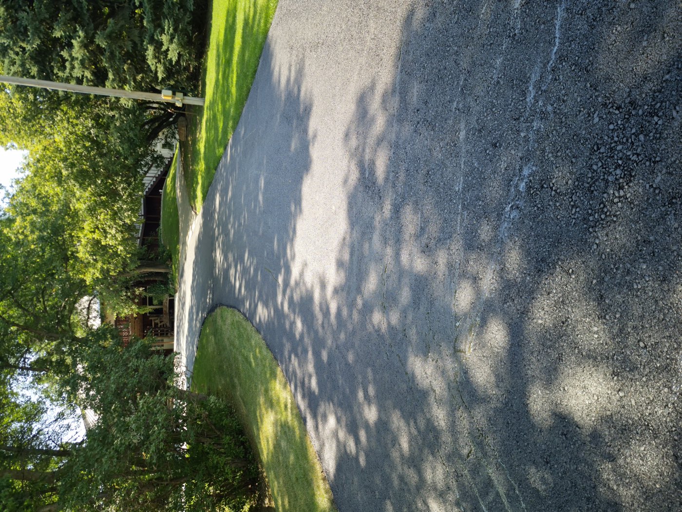 New asphalt driveway curving up to a home through a wooded lot near Williston, ND