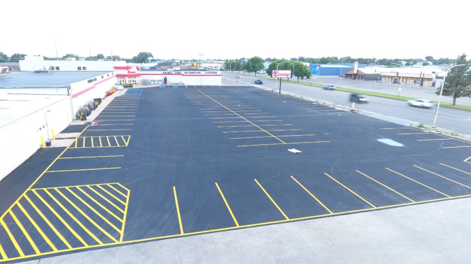 Fresh yellow line striping across a large retail parking lot in Williston, ND